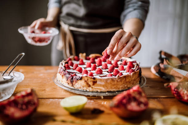Woman putting raspberries to american blackberry pie, while it is in mold